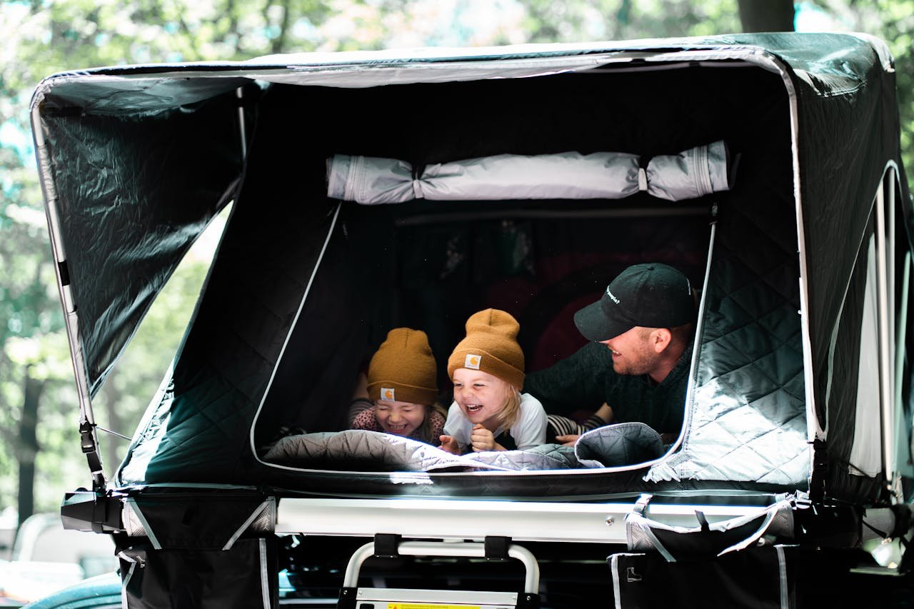 „Reisen mit Kindern mit dem Wohnmobil: Familie vor dem Wohnmobil auf dem Campingplatz“

